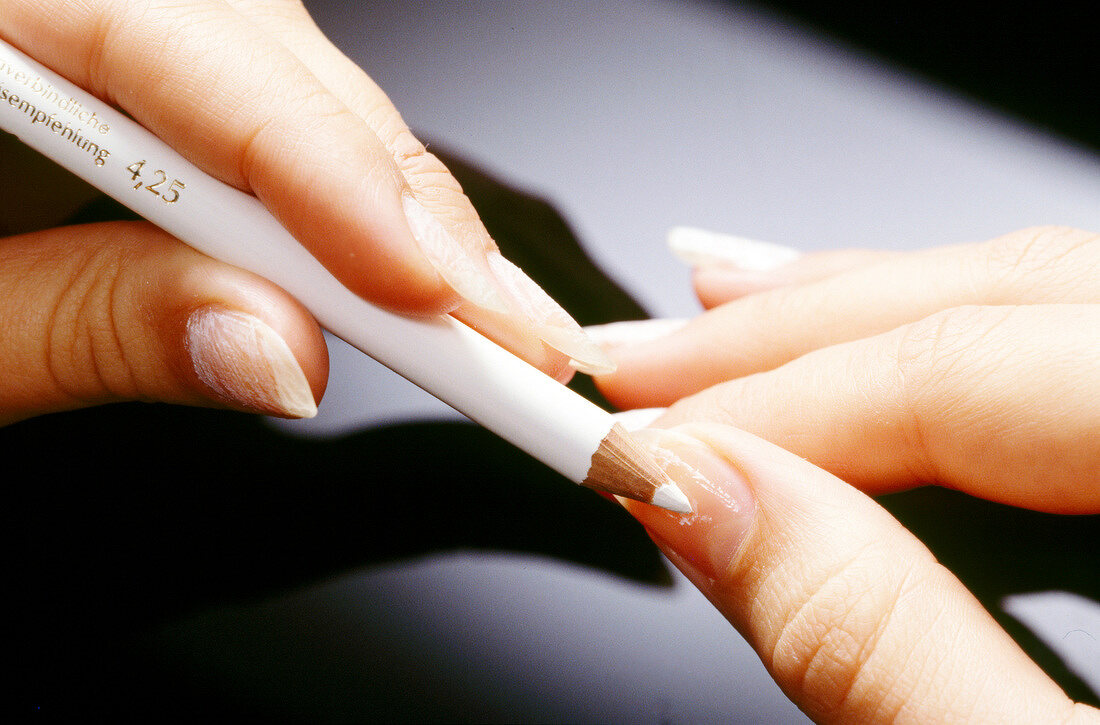 Close-up of woman applying white paint on nail