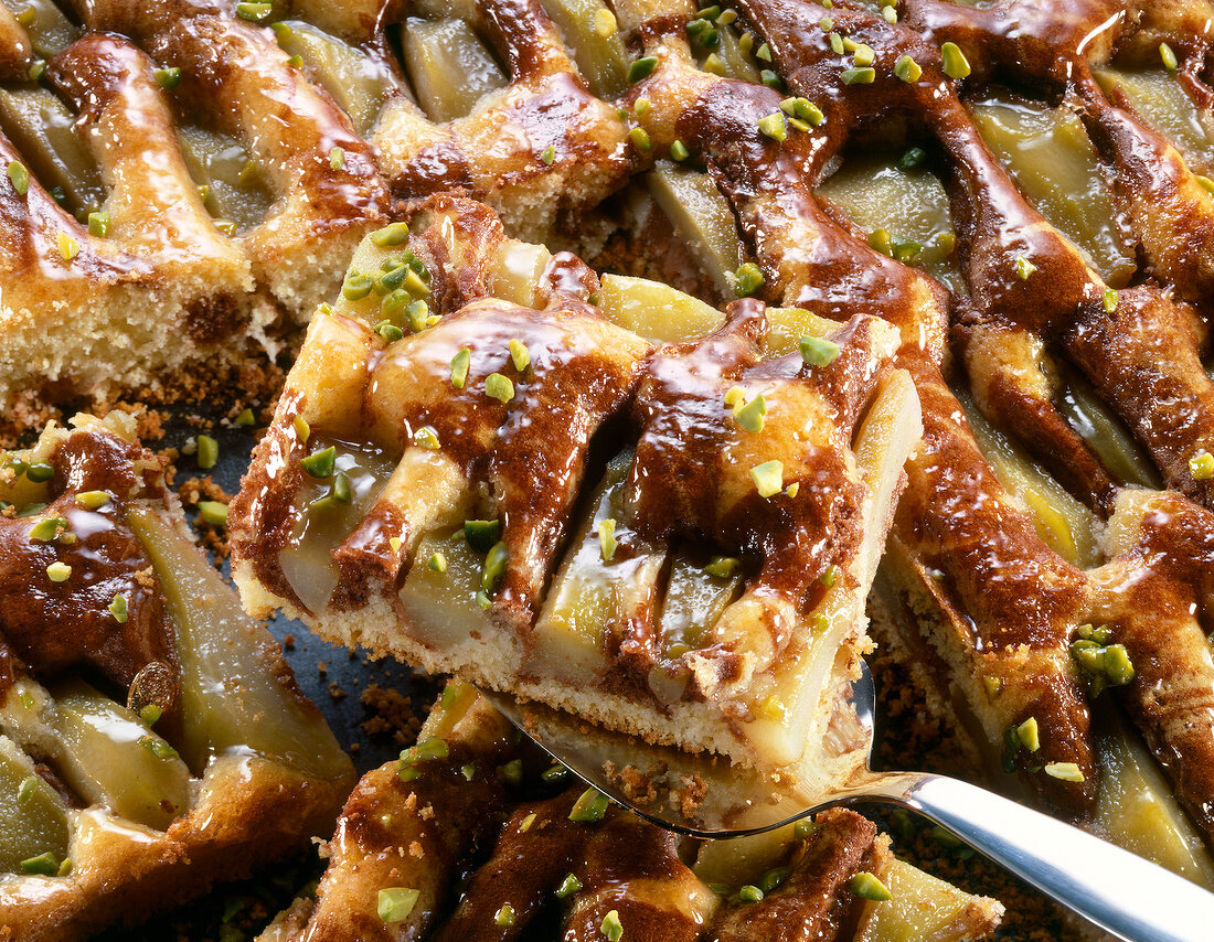 Close-up of pear marble cake with quince jelly, chopped pistachios and a slice on spatula