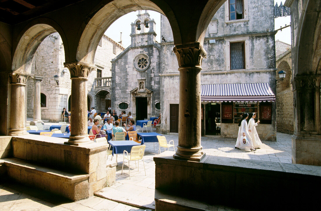 Guests at sidewalk cafe at main square in old town on Korcula island in Croatia