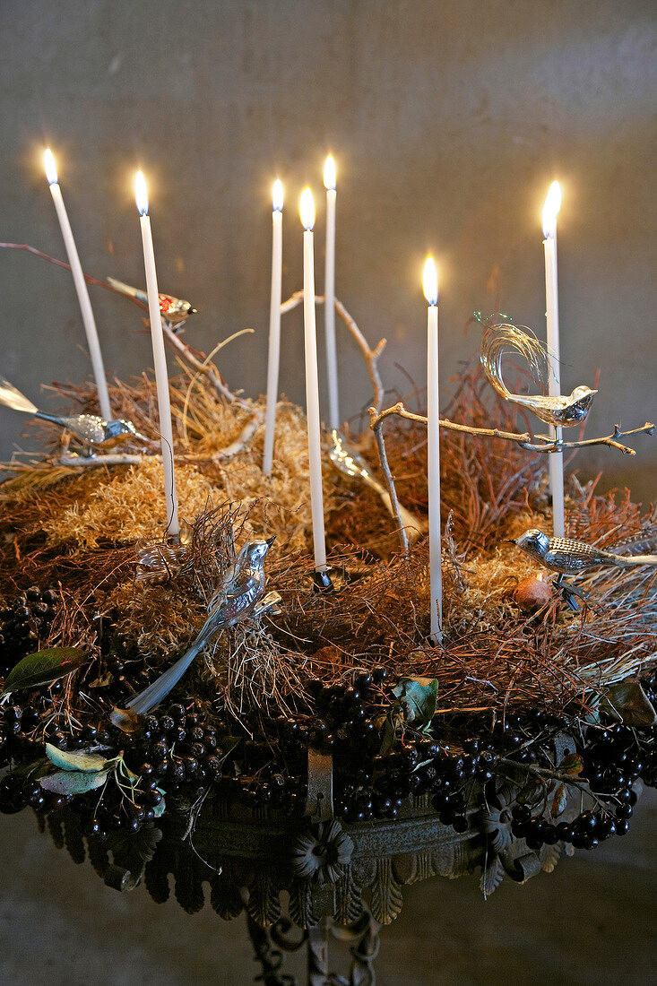 Close-up of bird nest decorated with lit candles and artificial birds made of metal