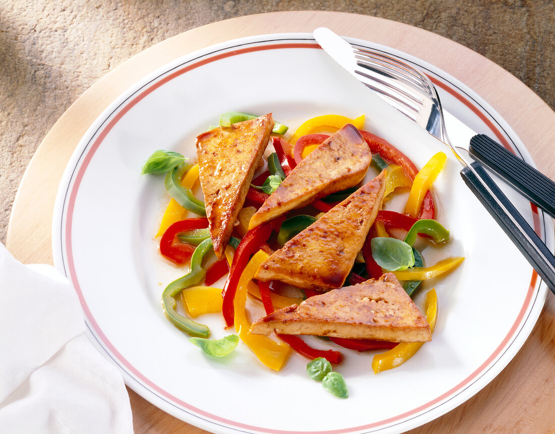 Fried tofu with red, yellow and green peppers on plate