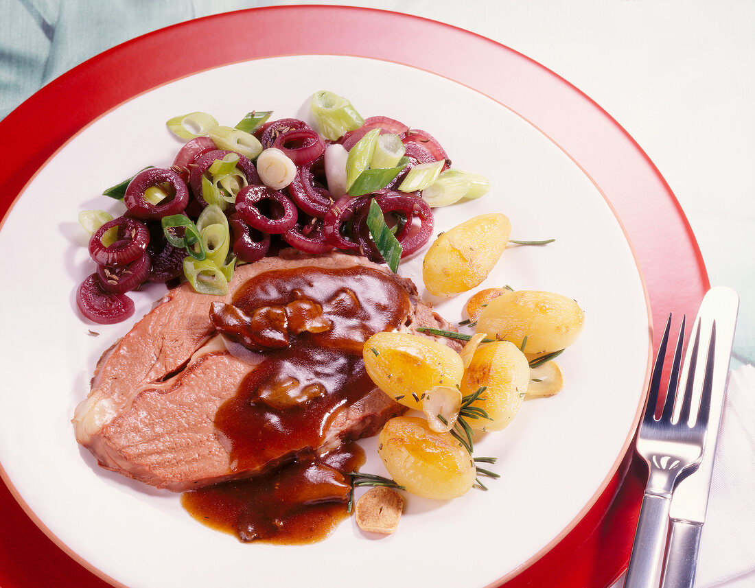 Prime rib with red wine onions and rosemary potatoes on plate