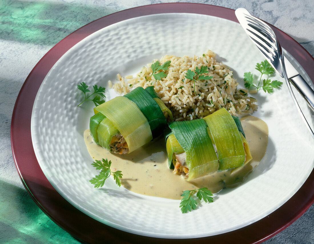 Tofu wrapped with leek with brown rice garnished with coriander on plate