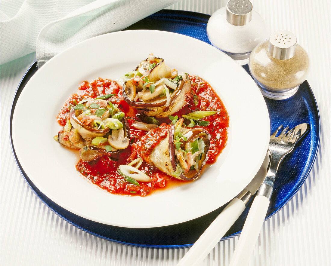 Stuffed eggplant slices with tomato puree and herbs on plate