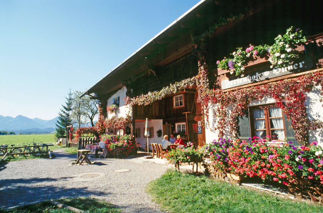 Landgasthof Huber in Bayern, Gäste sitzen an Tischen vor dem Haus