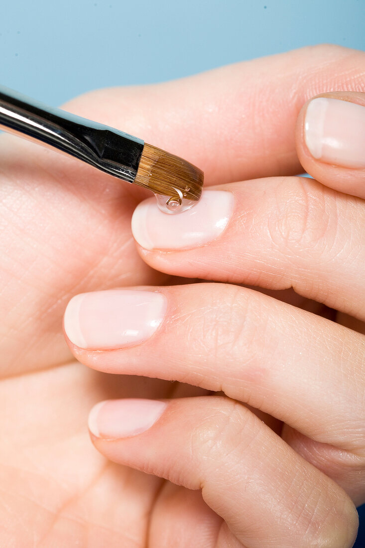 Hand einer Frau, Fingernagel wird mit Gel bestrichen