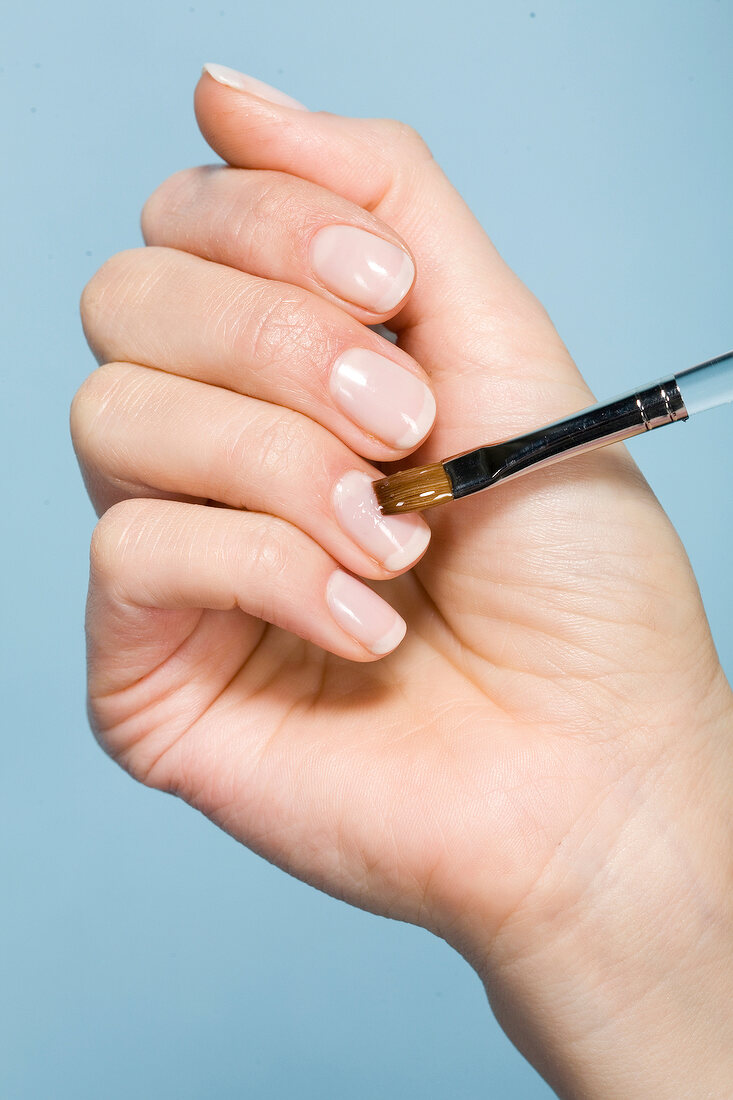 Close-up of woman applying gel on nails with brush