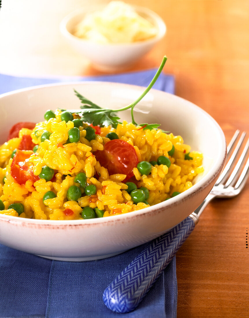 Close-up of saffron risotto with tomatoes and peas in bowl