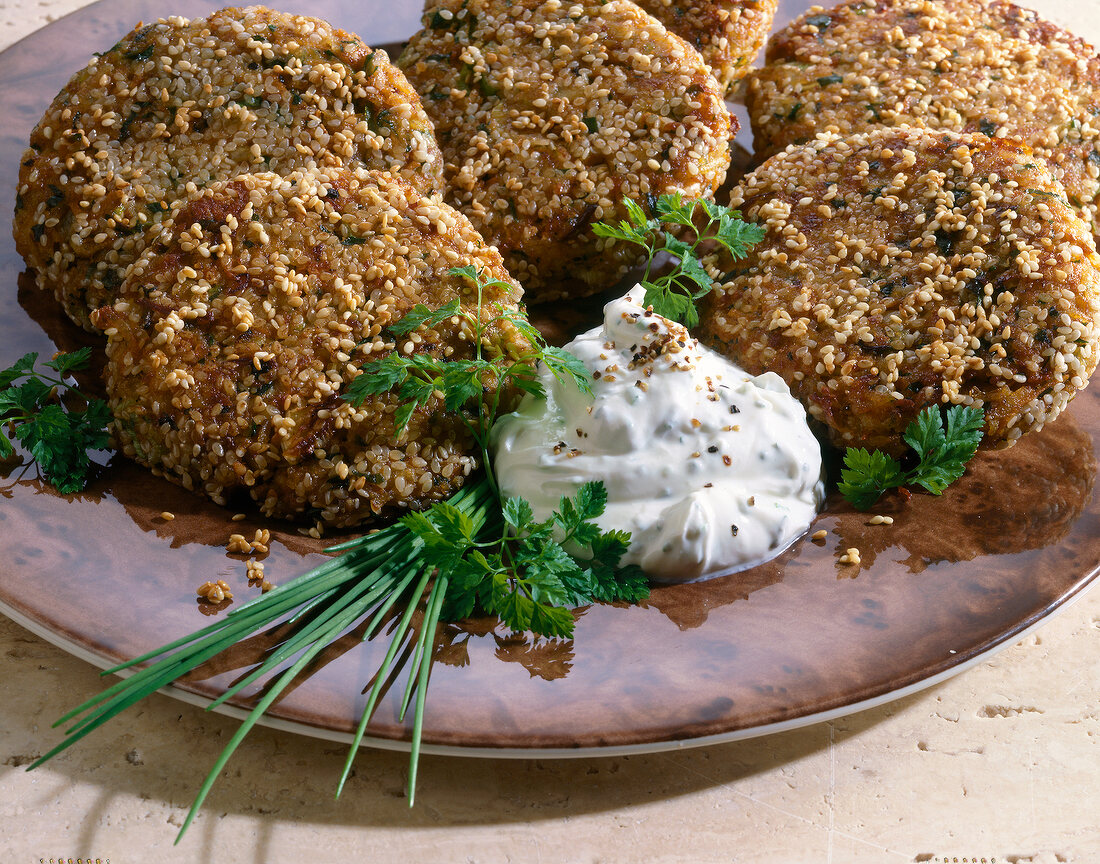 Close-up of sesame burgers on cream cheese with parsley and chives on plate