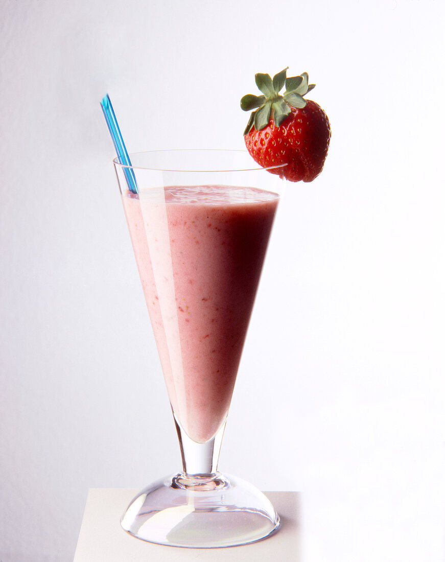 Glass of strawberry juice with strawberry on rim