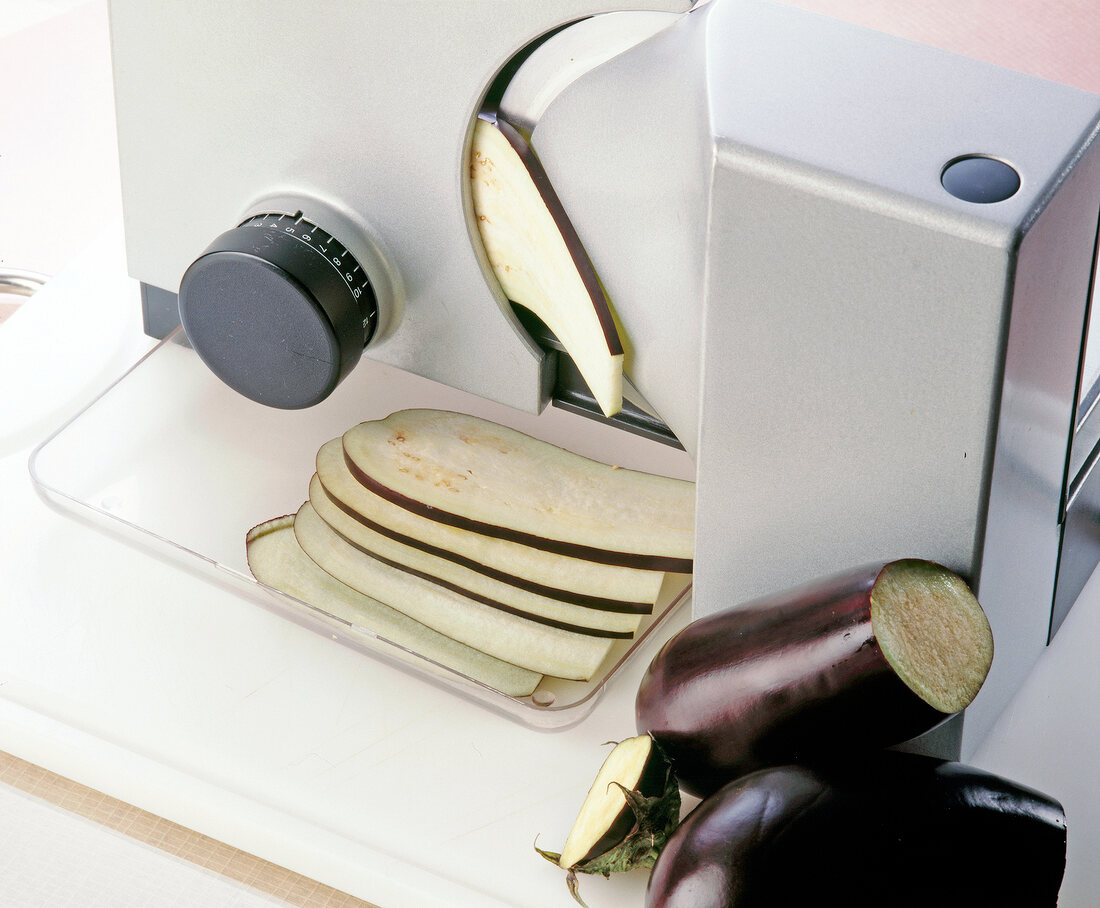 https://media01.stockfood.com/largepreviews/MzE1MzY1ODUy/10173092-Cutting-eggplant-slices-into-bread-slicer.jpg