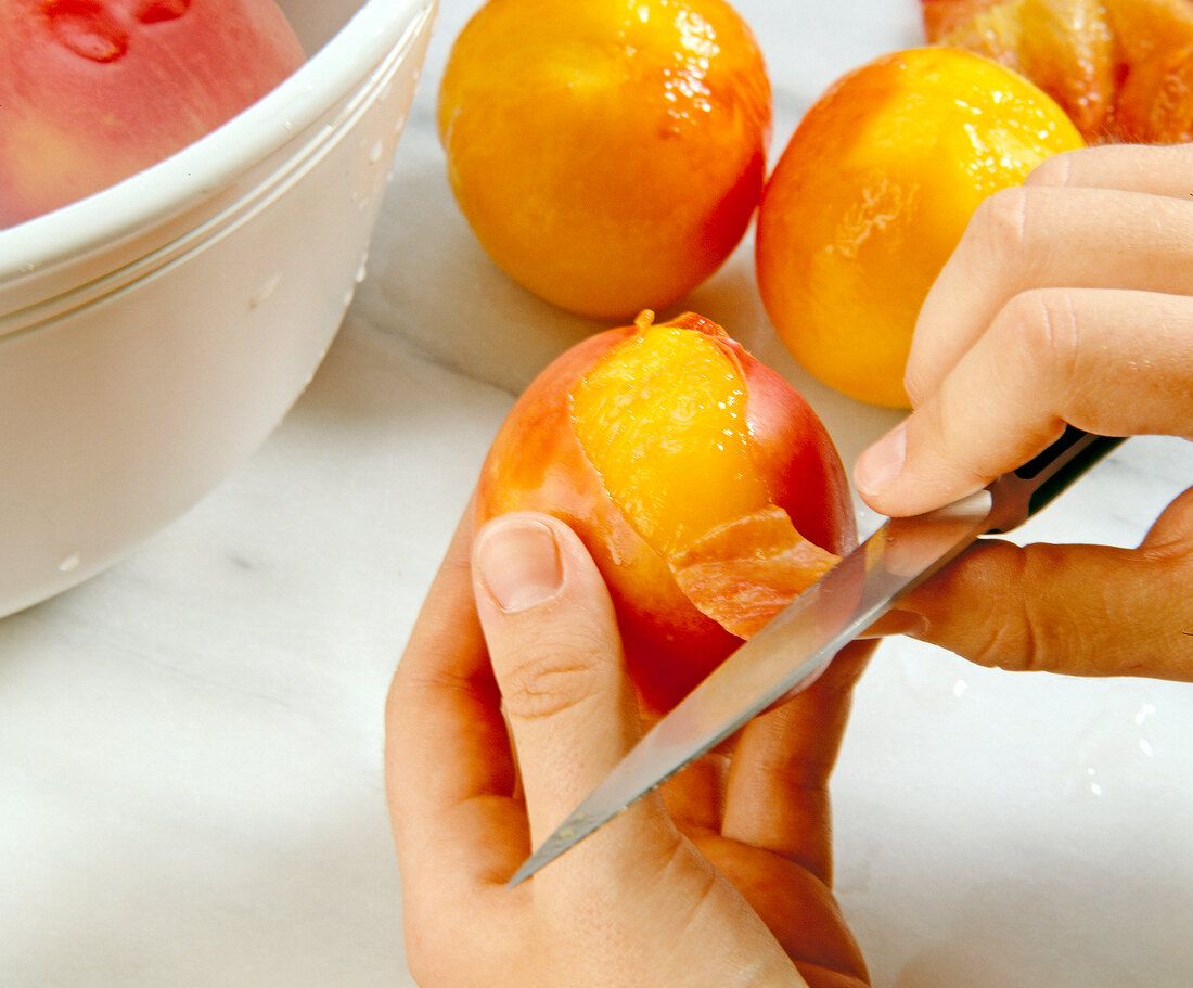 Close-up of nectarines being peeled with kitchen knife