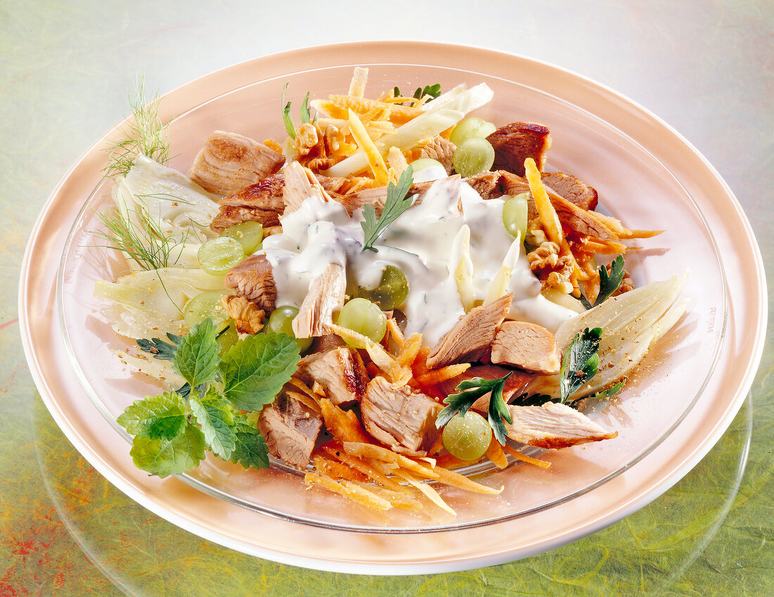 Close-up of chicken salad with fennel, nuts, grapes and carrots in plate
