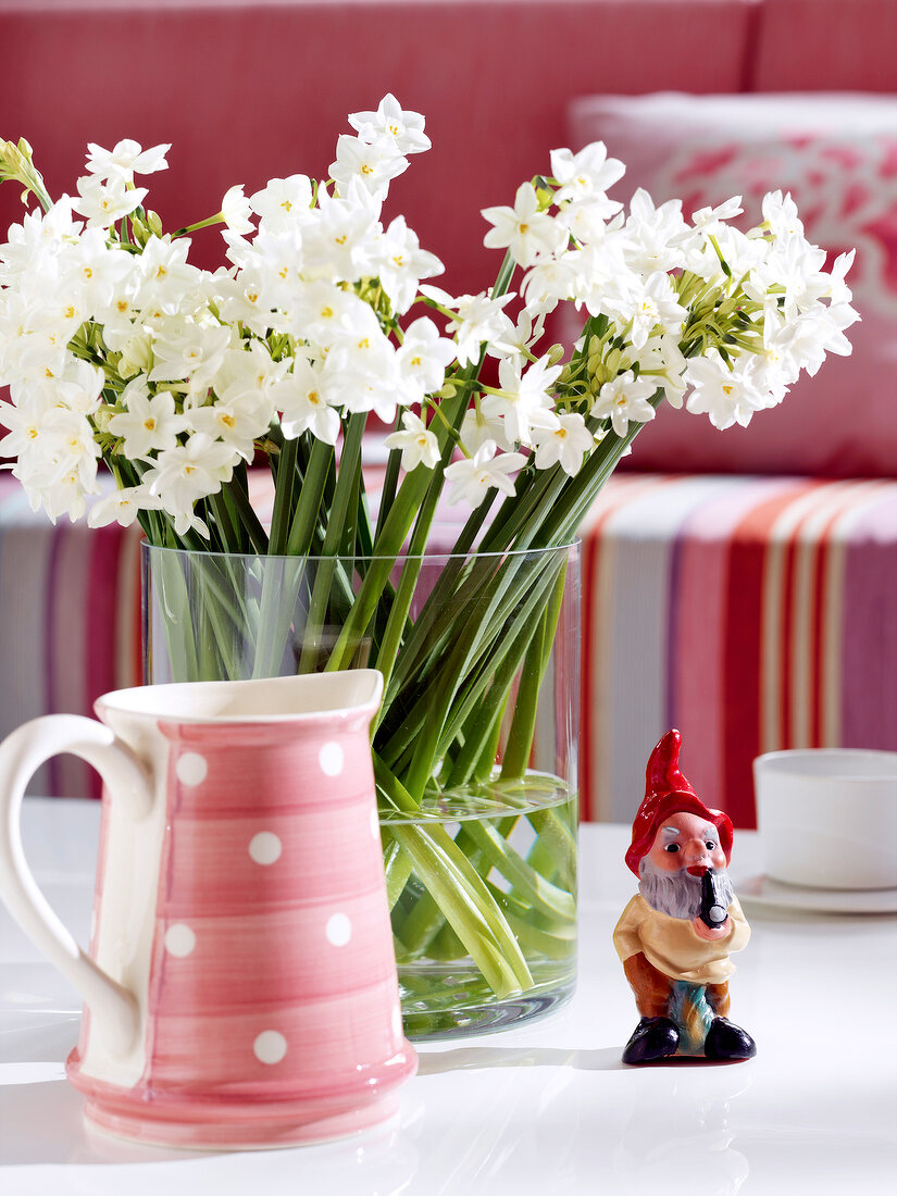 Tischdeko: Zwergfigur, gepunktete Kanne und Vase mit weißen Blumen.