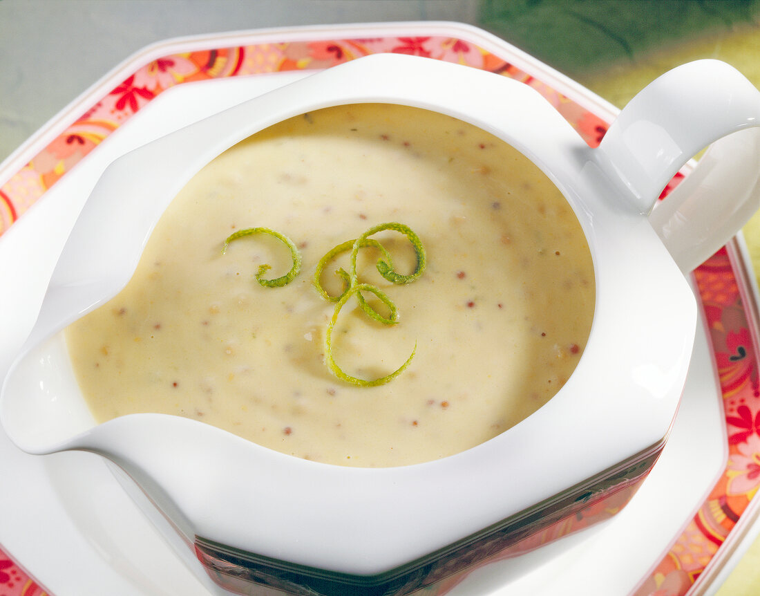 Grainy mustard cream sauce with lime zest in white gravy boat