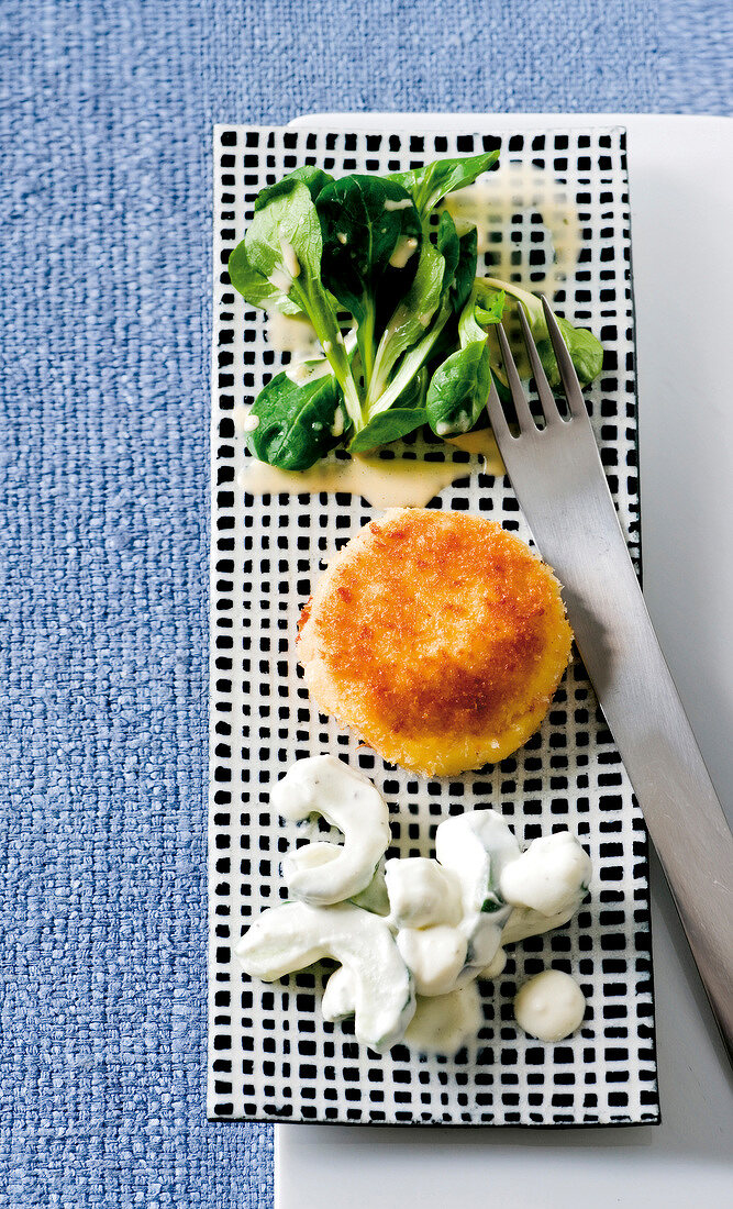 Crab cakes with corn salad and cucumber on tray