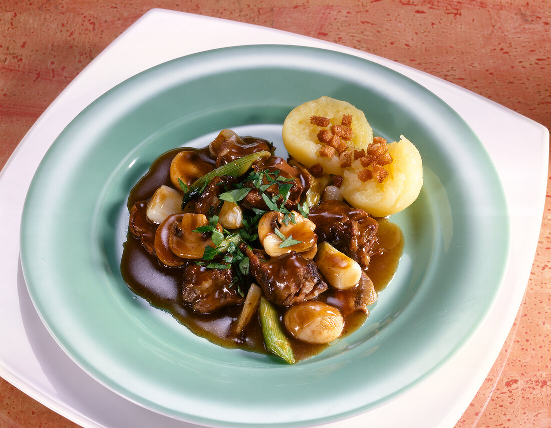 Oxtail stew with red wine, mushrooms and potatoes on plate