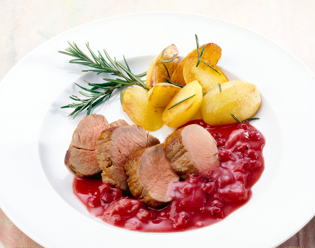 Pork with fruit sauce of rhubarb and berries, rosemary and potatoes on plate