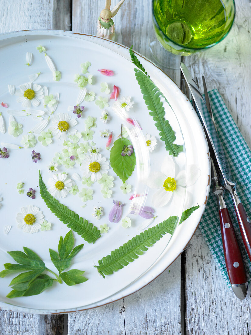 Freshly picked flowers on plate with glass and knife