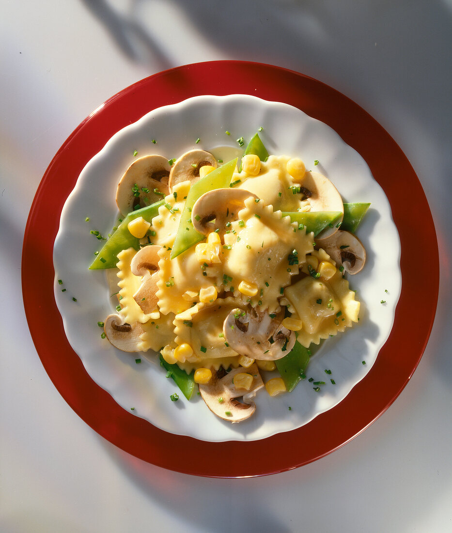 Nudelsalat mit Zuckererbsen und Champignons auf rotem Teller