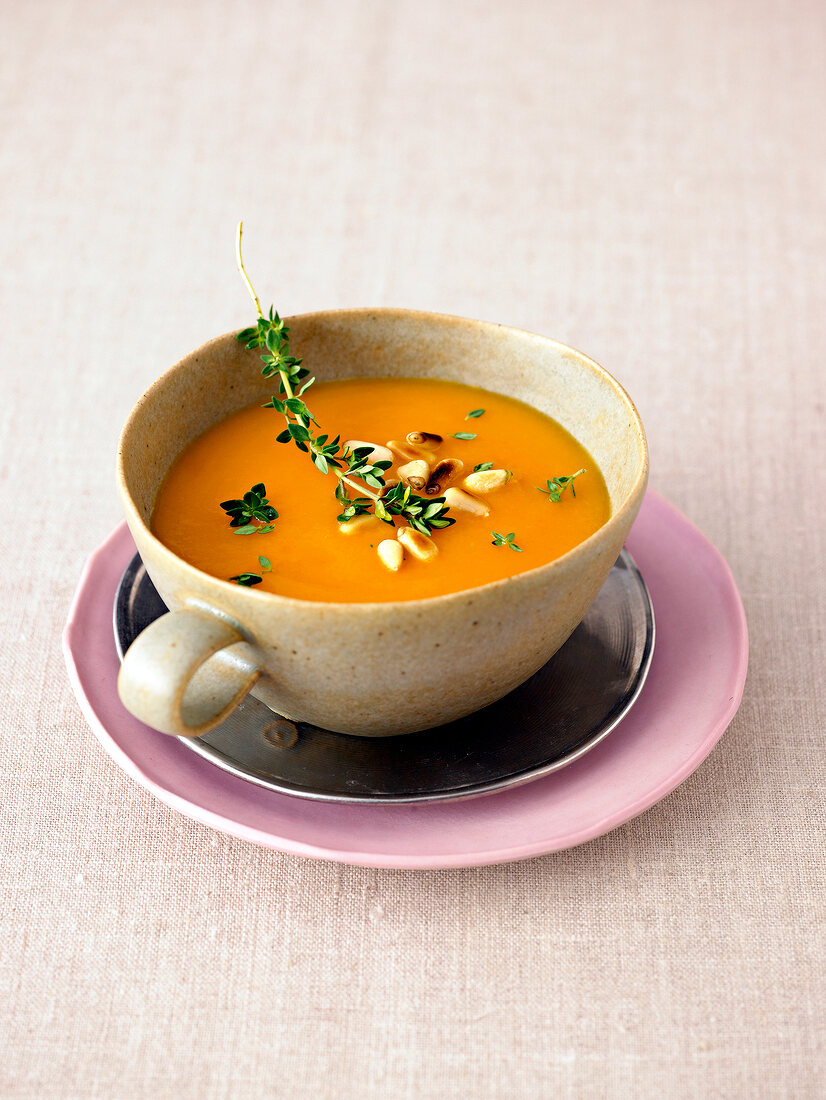 Potato and carrot soup with pine nuts in cup