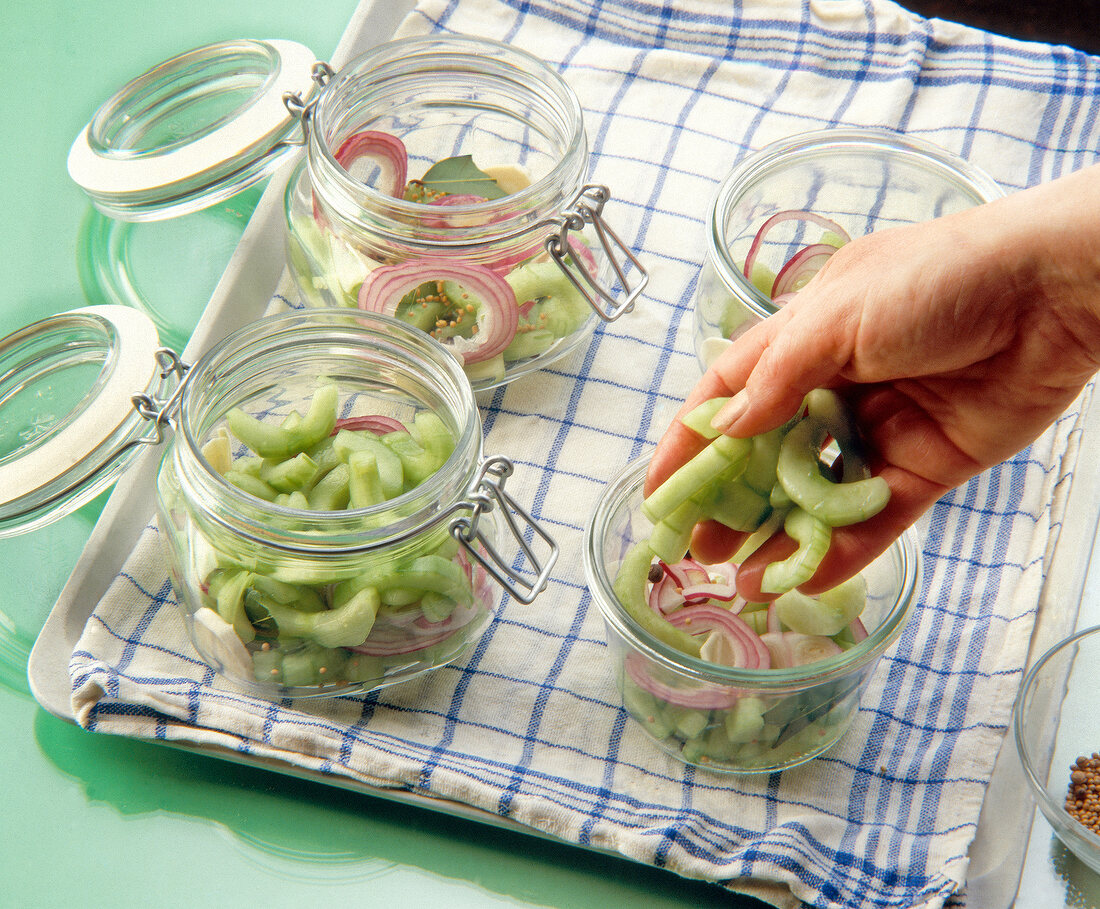 Woman filling cucumber slices in glass jar