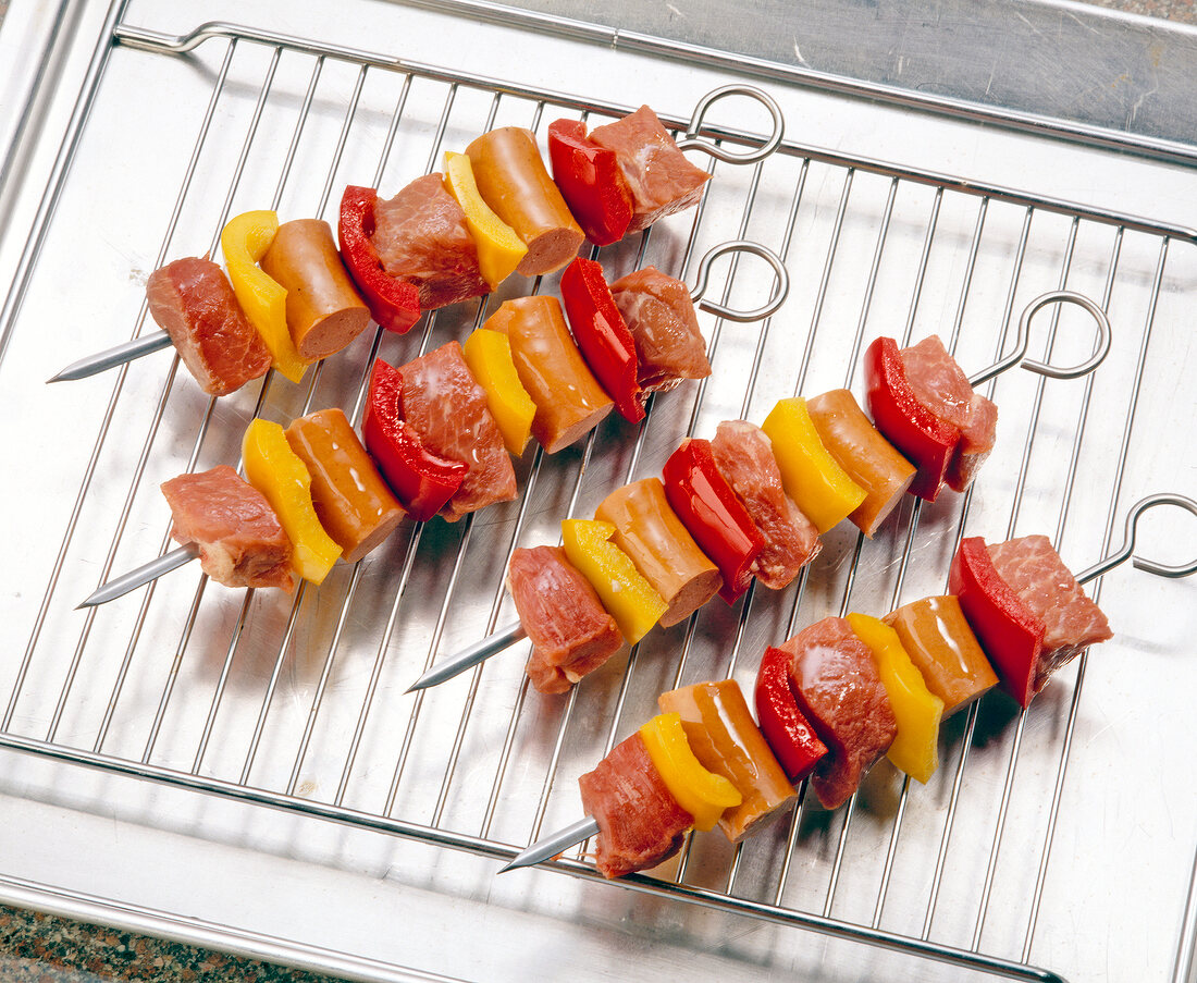 Close-up of four barbecue skewers on wire rack