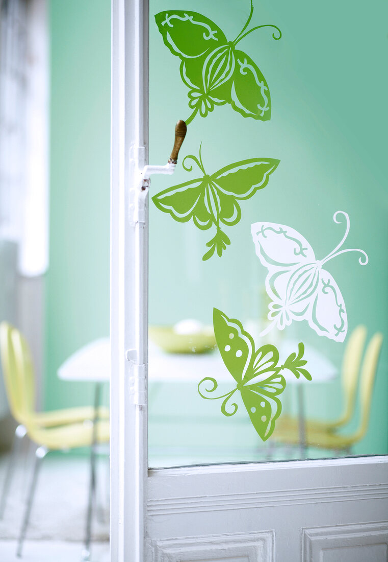Close-up of green and white butterfly design on window glass