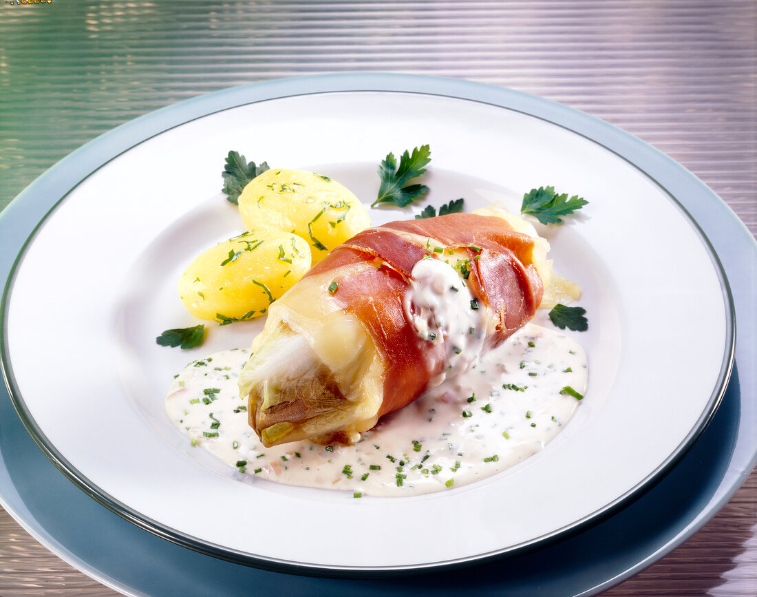 Chicory with cheese sauce and potatoes on plate