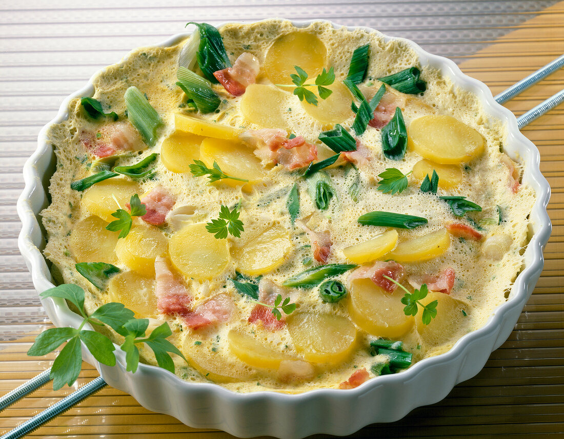 Potato omelette with bacon and green onions in bowl