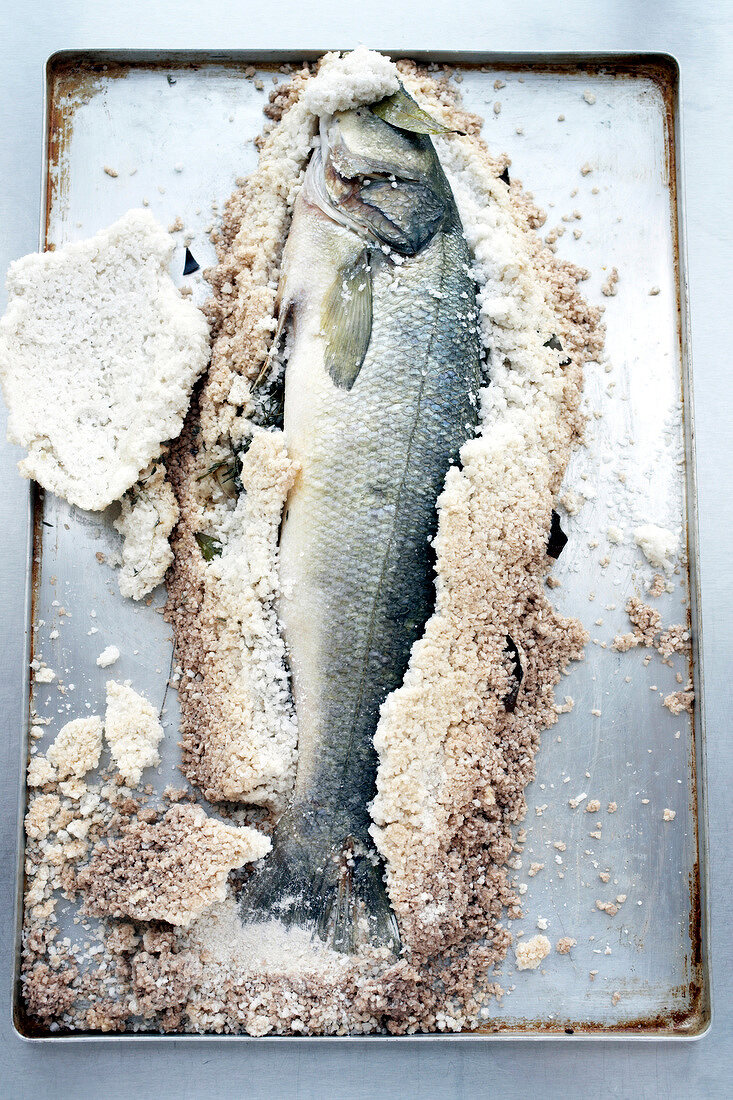 Sea bass with disrupted salt crust on baking tray