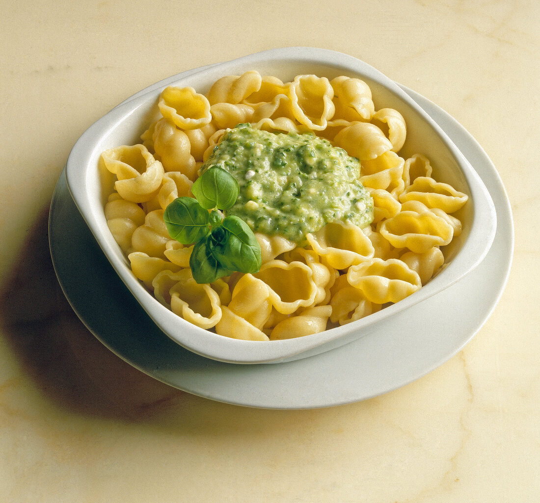 Close-up of pasta shells with zucchini sauce and basil in bowl