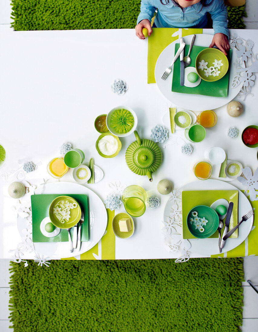 Breakfast table setting in green and white for Easter, overhead view