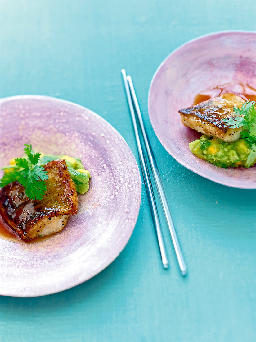 Zander teriyaki with avocado, mango puree and coriander leaves on plate