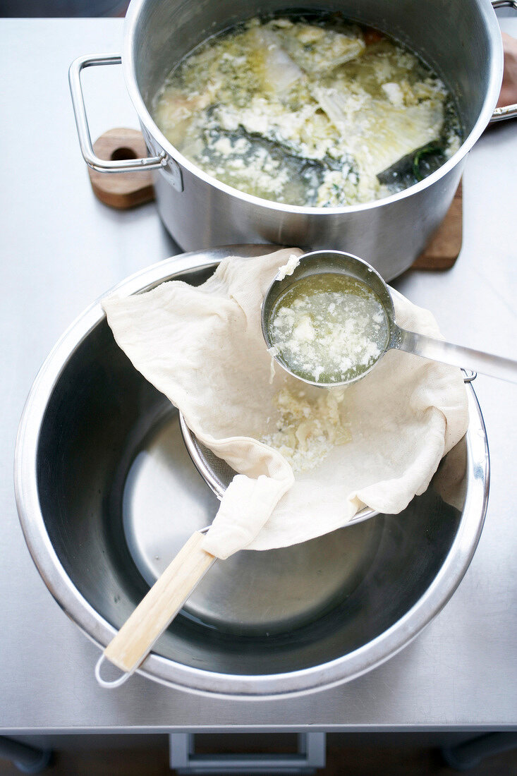 Stock being strained in a bowl through cloth, step 3