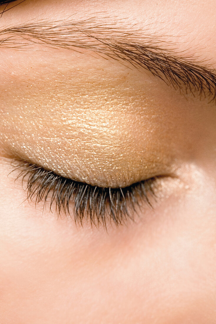 Extreme close-up of woman's eye with golden eye shadow