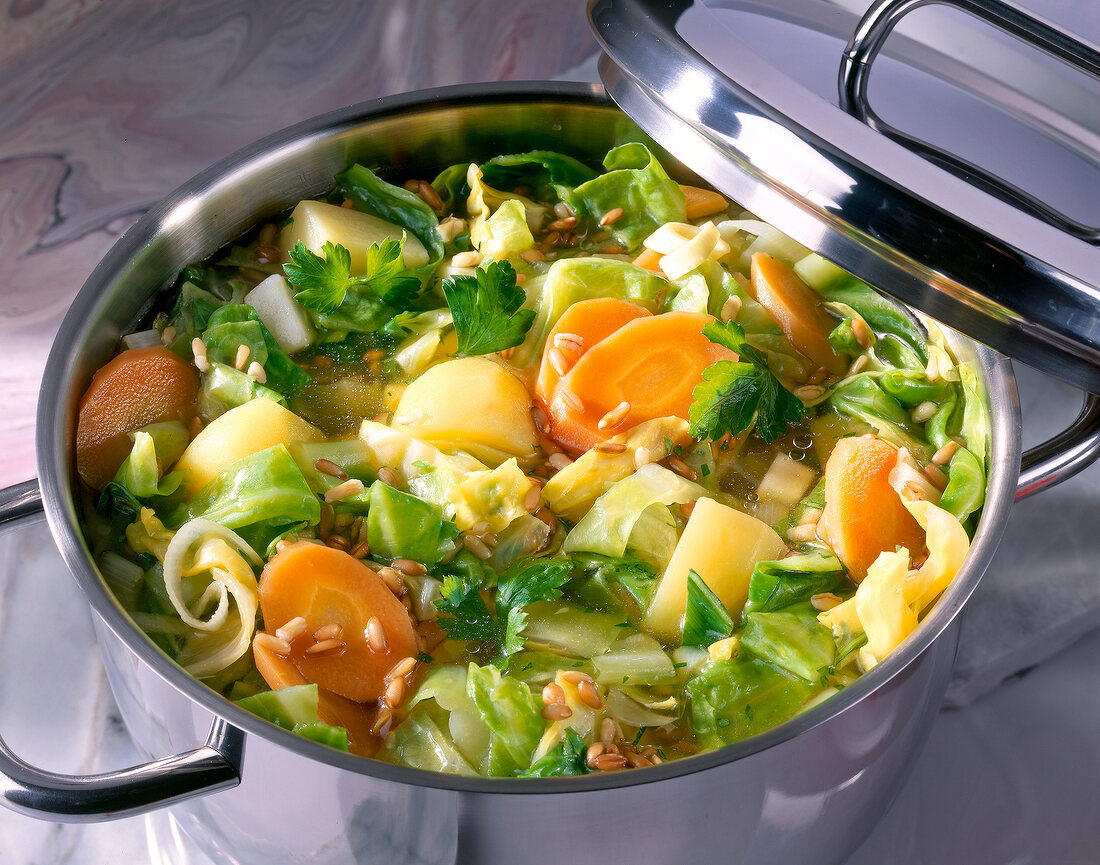 Close-up of cabbage stew with carrots, potatoes and celery in casserole with lid