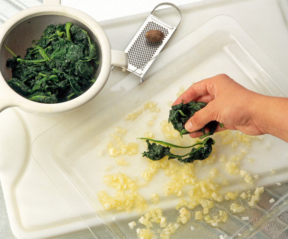 Placing spinach on transparent tray with chopped onions