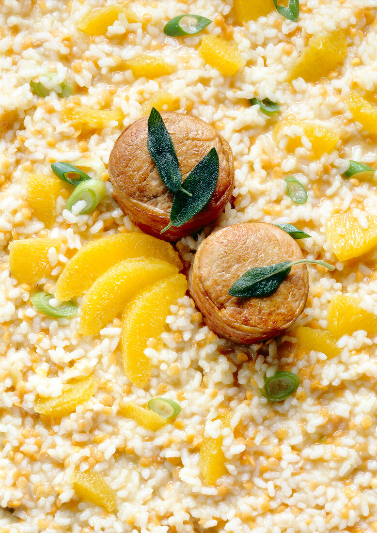 Pork medallions on orange risotto with sage leaves, overhead view