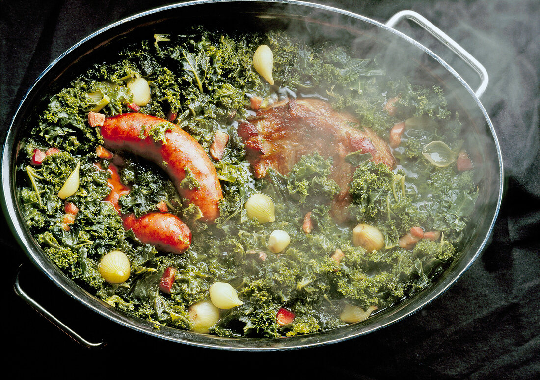 Steamed kale, cabbage, sausages, pork cheek and onion in pot