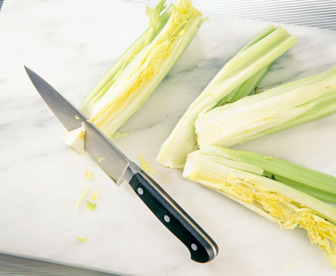 Cutting celery with knife on cutting board