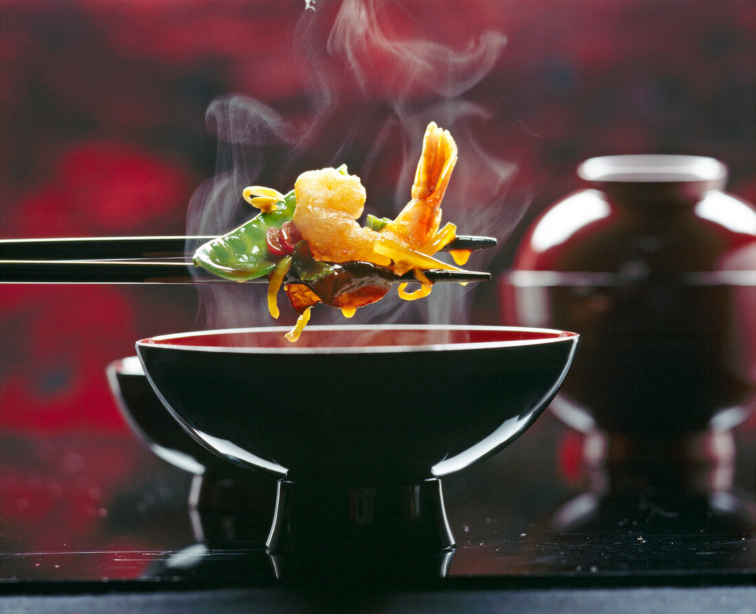 Deep-fried curried shrimp with vegetables in china bowl with chopsticks