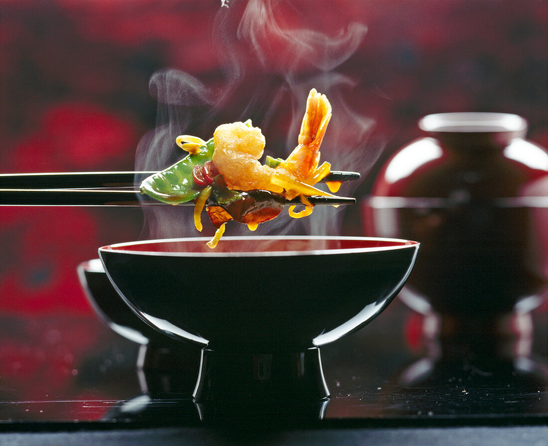 Frittierte Curry-Garnelen mit Gemüse in einer China-Schüssel mit Stäbchen