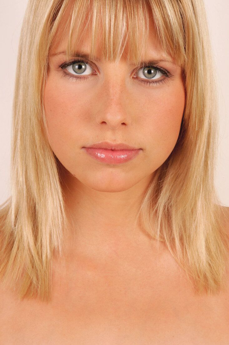 Portrait of beautiful green eyed blonde woman with bangs, close-up