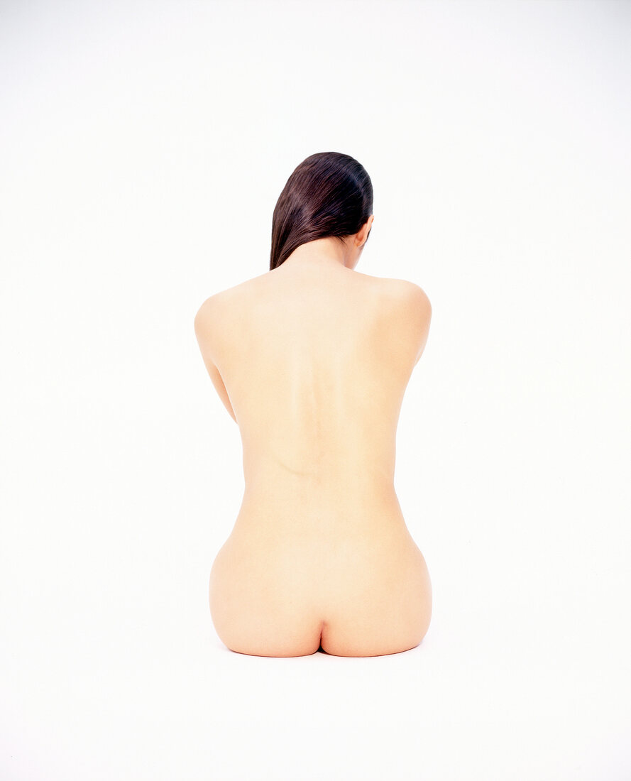 Rear view of nude woman sitting against white background