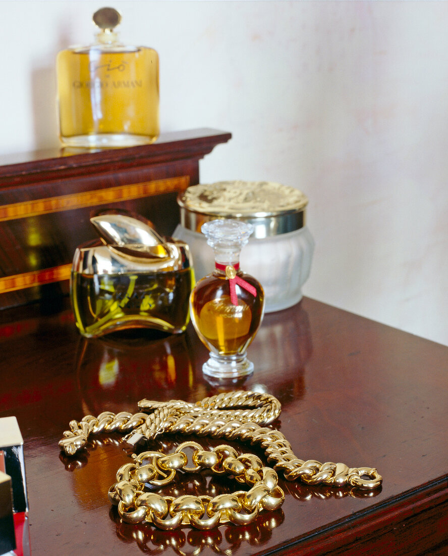 Close-up of gold bracelets and bottles of perfumes on table