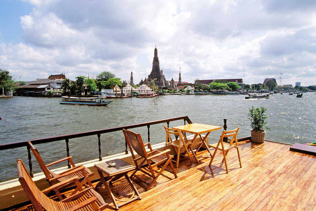View of river, boats, buildings and temples from deck of boat in Bangkok
