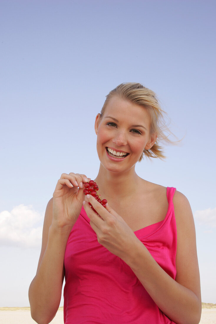 Laughing woman holding a bunch of red currants