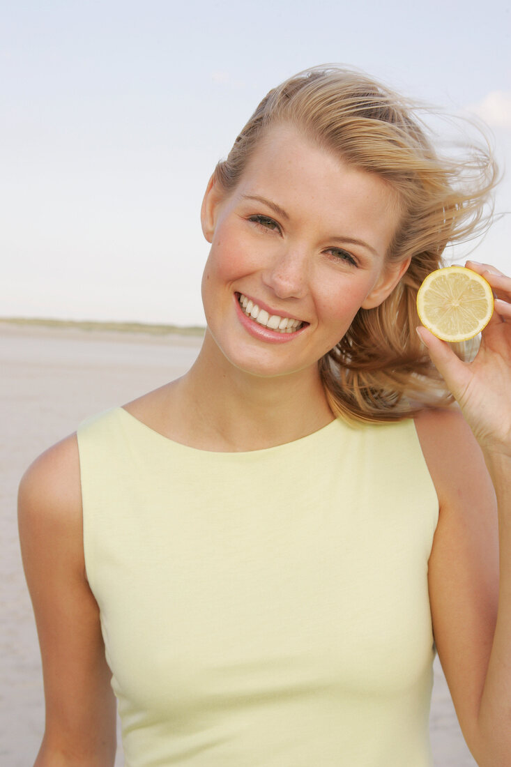 Woman holding slice of lemon, smiling
