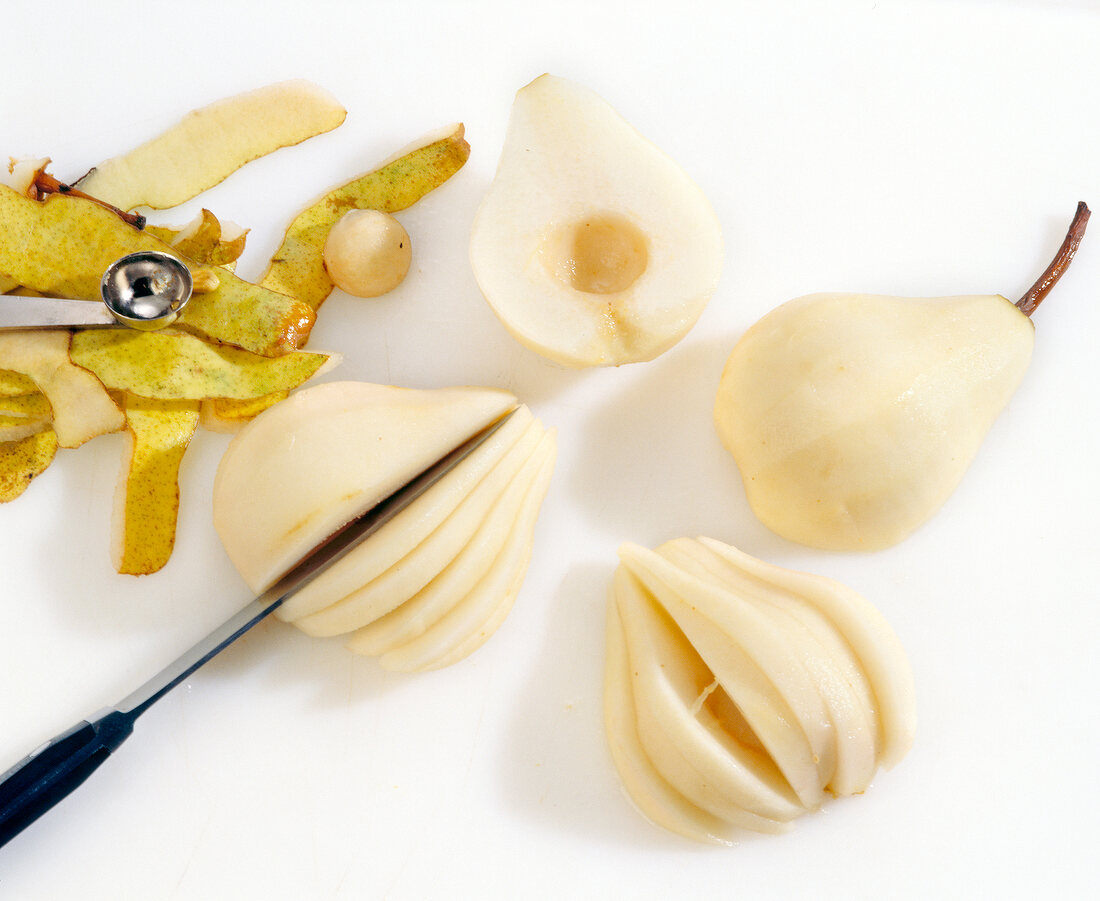 Peeled pears being cut into wedges on cutting board